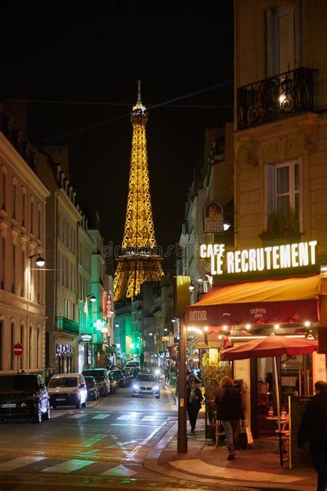 Eiffel Tower Illuminated At Night And Street With People And Typical