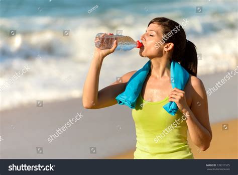 fitness beautiful woman drinking water and sweating after exercising on summer hot day in beach