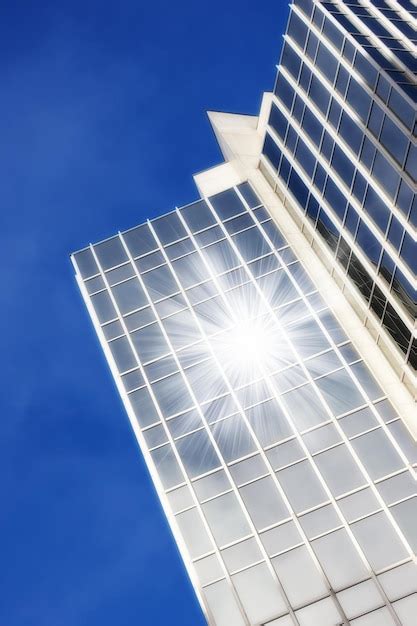 Ventanas de vidrio geométricas en un rascacielos con sol que refleja un