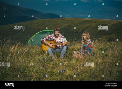 Romantic Couple Plays Guitar On Camping Outdoor Adventure With Friends