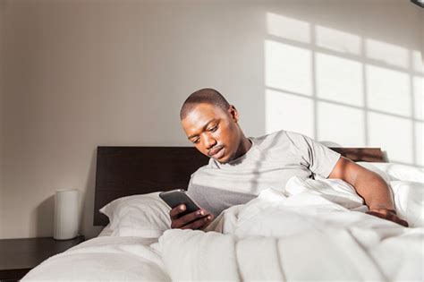 Businessman Waking Up In Bed Texting On His Phone In The Morning Stock