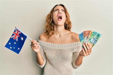 Young Caucasian Woman Holding Australian Flag And Dollars Angry And Mad Screaming Frustrated And
