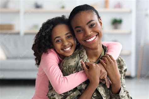 Retrato De Uma Adolescente Negra Alegre Abraçando Seu Soldado Mãe