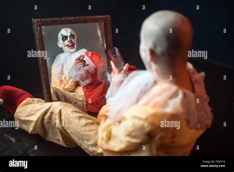 Portrait Of Scary Bloody Clown With Crazy Eyes Sitting At The Mirror