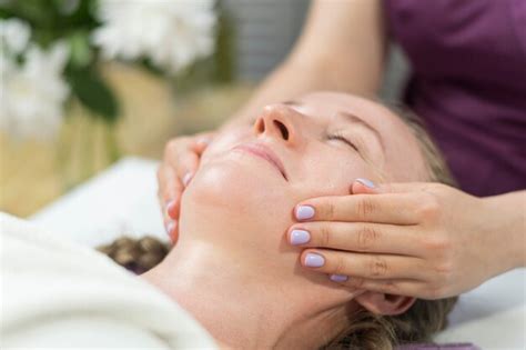 as mãos do massagista fazem modelagem de massagem facial para jovem relaxar no salão spa vista