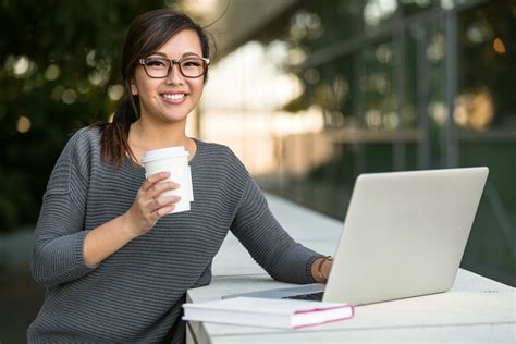 Pretty female student smiling happy browsing the internet on college campus laptop