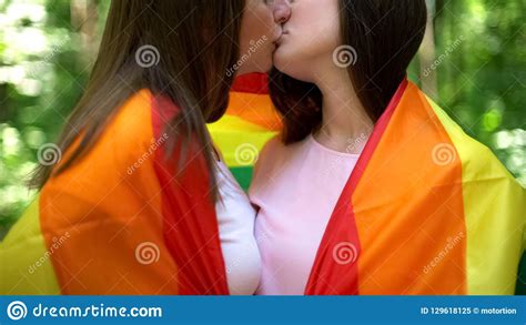 lesbianas envueltas en la bandera del arco iris que se besa relaciones del mismo sexo las