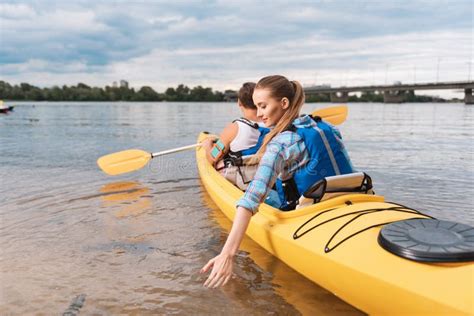 Blonde Haired Woman Putting Her Hand In Water While Kayaking Stock