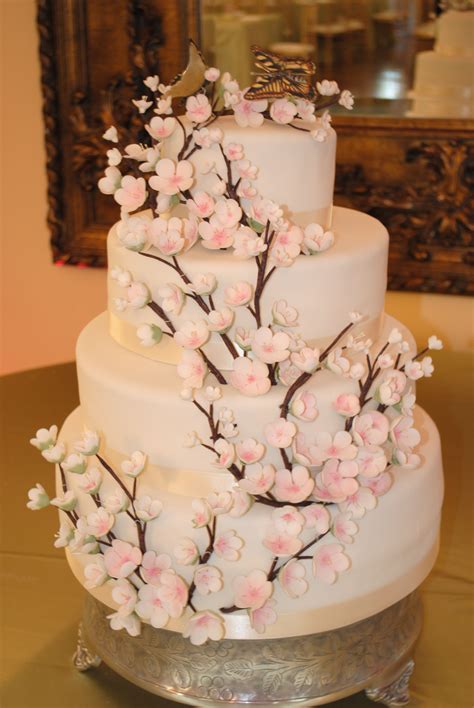 A Three Tiered Wedding Cake With Pink Flowers On The Top And Bottom Sitting On A Table In Front