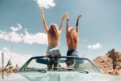 Rear View Of Women Topless In Convertible Car Arms Raised Stock Photo