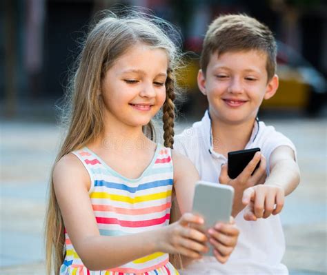 Two Kids With Mobile Phones Outdoors Stock Photo Image Of Expression