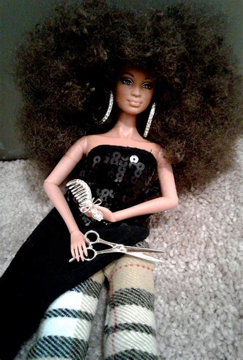 A Doll With An Afro Sitting On Top Of A Bed Next To A Pair Of Scissors