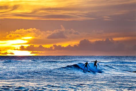 Sunset Surfers Surfing Scenic Hawaiian Ocean Off Poipu Beach Kauai