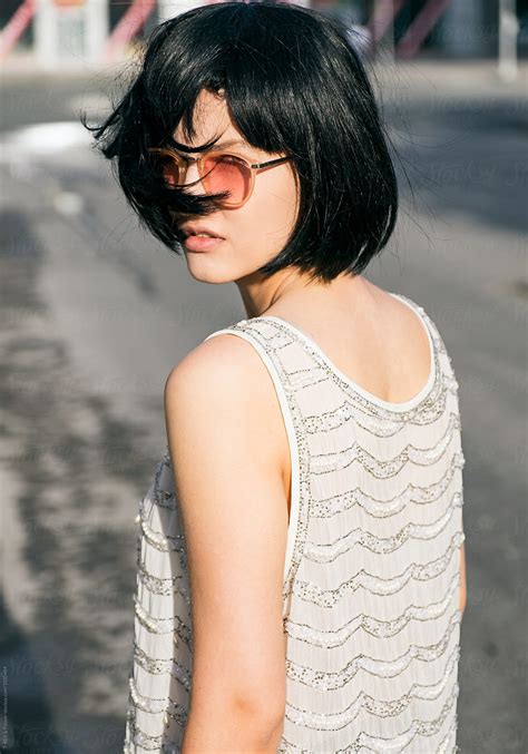 attractive black haired girl in sunglasses looking at camera overshoulder del colaborador de