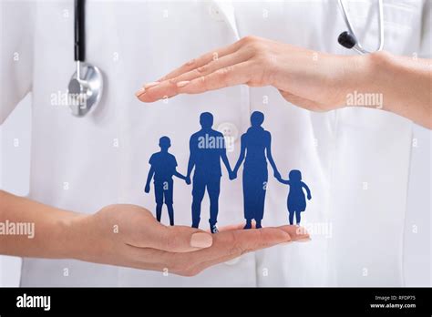 Close-up Of Doctor's Hand Protecting The Blue Family Paper Cut Out