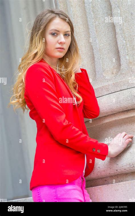 Dressing In A Red Blazer A Blonde Teenage Girl Is Standing By A Column Thoughtfully Looking At