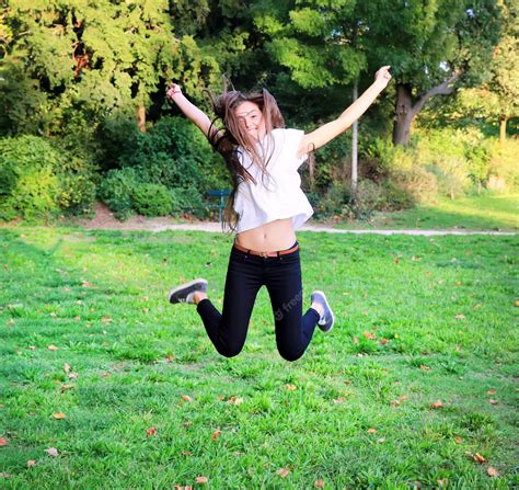 hermosa jovencita feliz saltando alto en el parque foto premium