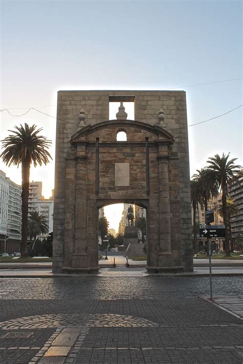 An Arch In The Middle Of A Street With Palm Trees