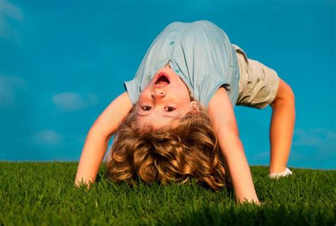 Happy Boy Doing A Headstand On The Grass In The Summer Sunshine Funny