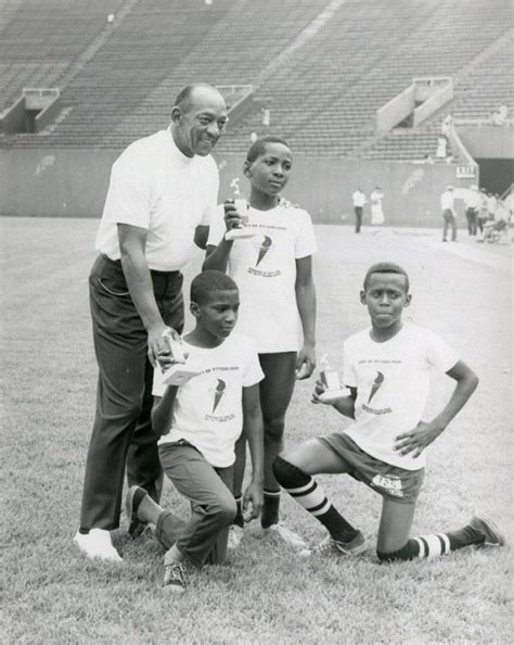 Jesse Owens Poses With Three Young Trophy Winners At A Track Meet