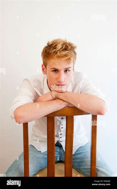 Young Man Sitting Astride The Chair Leaning On The Back And Looking At