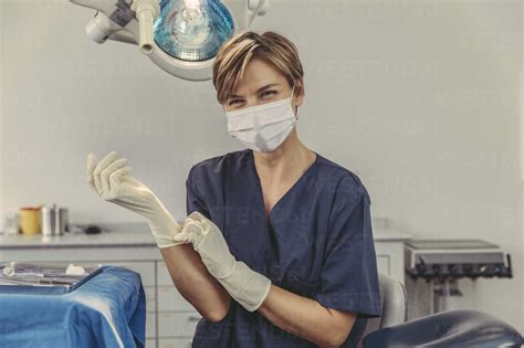 Dental Surgeon Wearing Surgical Mask Putting On Surgical Gloves Stock