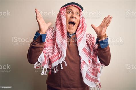 senior handsome arab man wearing keffiyeh standing over isolated white background celebrating