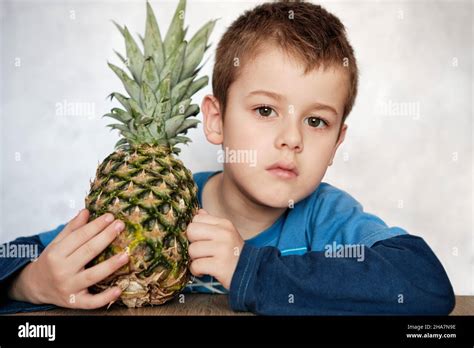 Cute Caucasian 7 Year Old Boy With Brown Eyes Holding A Pineapple