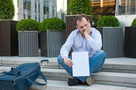 Sad Man Sitting On The Steps With A Suitcase Empty Sign Stock Photo