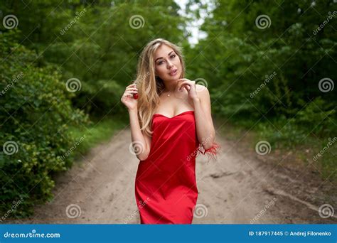 Beautiful Young Long Haired Blonde In A Red Dress Posing On The Road In