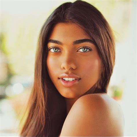 A Woman With Long Brown Hair And Blue Eyes Posing For A Photo In Front