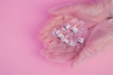 Unrecognizable scientist showing COVID 19 vaccines in pink studio ...