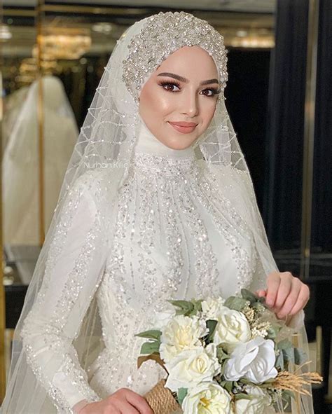 A Woman In A White Wedding Dress Holding A Bouquet Of Flowers And Wearing A Veil