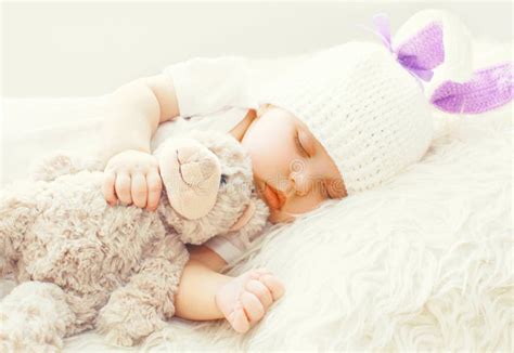 Cute Baby Sleeping With Teddy Bear Toy On White Soft Bed Stock Image