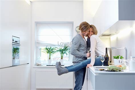 Couple In Kitchen Hugging Woman Sitting On Kitchen Counter Picture And