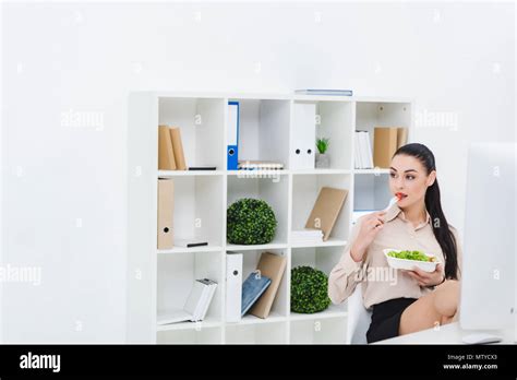 Portrait Of Businesswoman Eating Take Away Salad For Lunch At Workplace