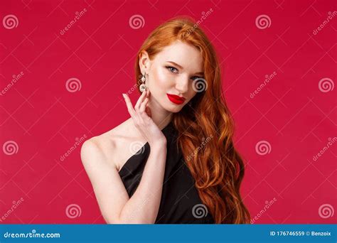 close up portrait of sensual seductive redhead woman with red lipstick touching earring