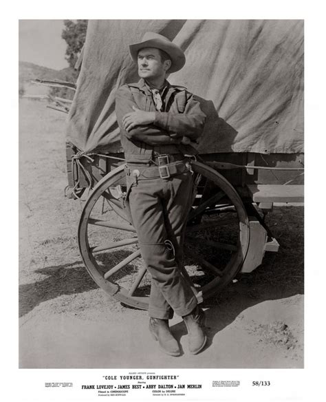 An Old Photo Of A Man In Uniform Standing Next To A Wagon With Wheels On It