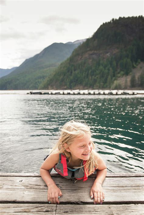 Girl Swimming In Mountain Lake Holding On To Wooden Dock Photograph By