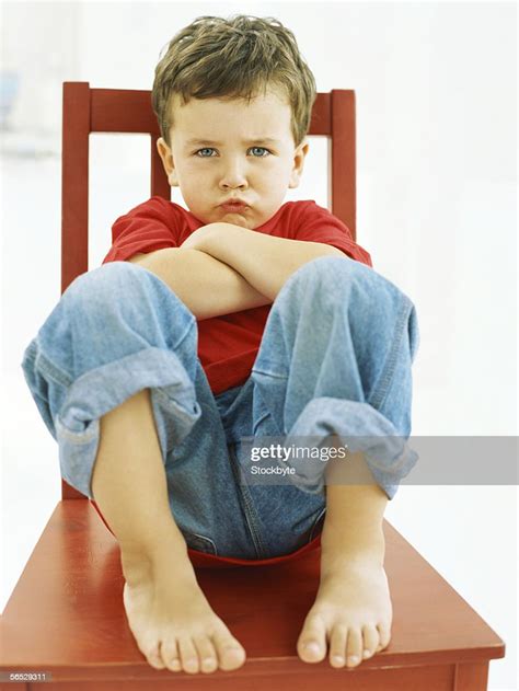 Portrait Of A Boy Sitting On A Chair Puckering His Lips High Res Stock