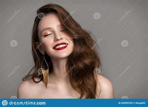 Portrait Of A Charming Brunette With Red Lips On A Gray Background