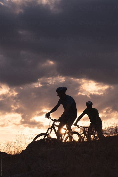 Sportsmen Silhouettes Riding Mountain Bikes With Sunset Sky In Backround By Stocksy