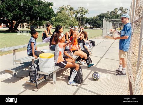 Teacher Questioning Schoolgirl Soccer Players On School Sports Field
