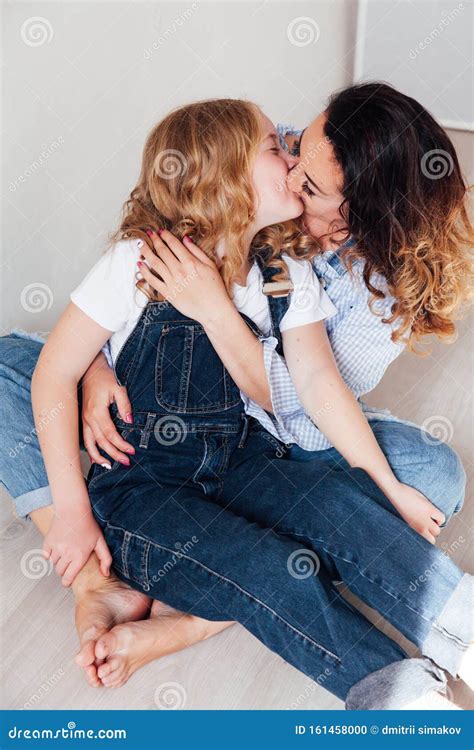 Mom And Daughter In Jeans Sit Together Cuddling Stock Photo Image Of