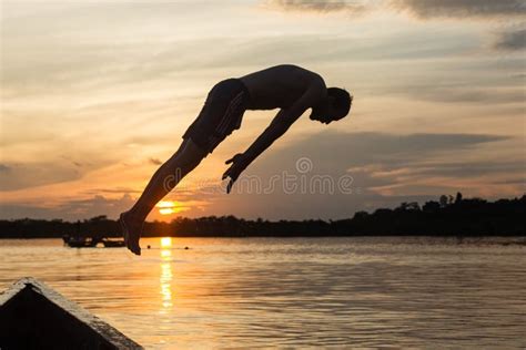 Man And Woman Jump Into The Water At Sunset Stock Image Image Of