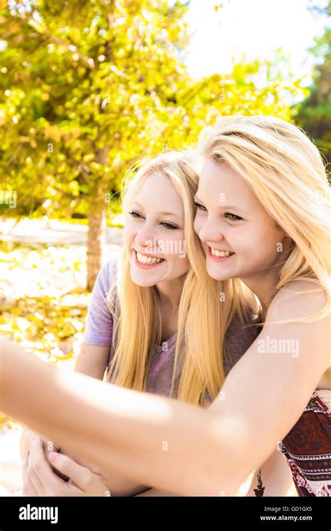 Two Sisters Having Fun In A City Park In Autumn And Talking A Selfie