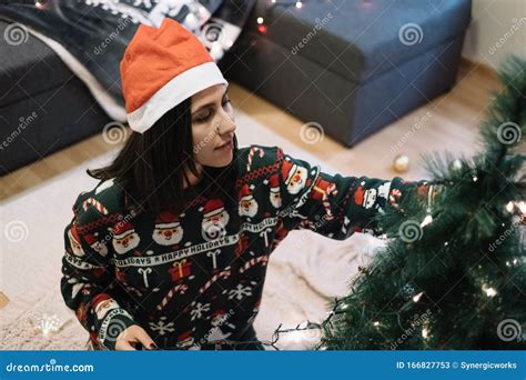 Woman In Green Holiday Sweater Placing Christmas Lights Stock Image