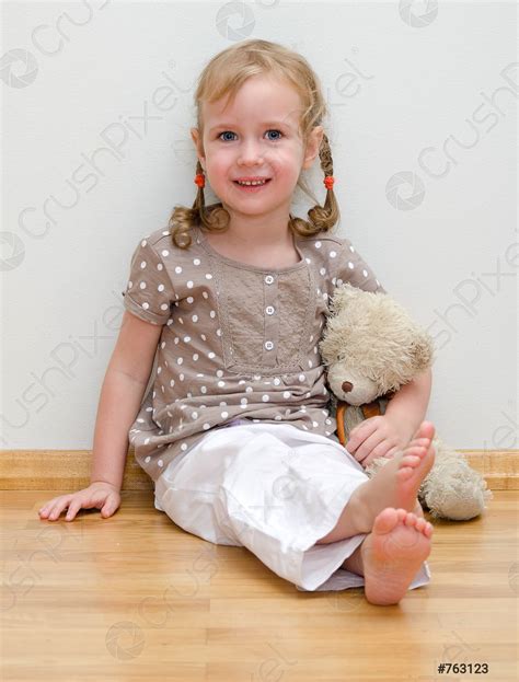 Cute Little Girl Sitting With Teddy Bear On The Floor Stock Photo