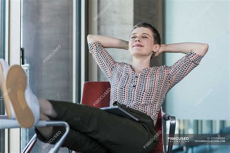 Relaxed Businesswoman With Closed Eyes Sitting On Chair In Office