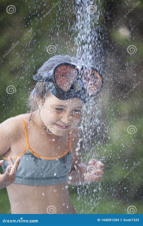 Little Girl In A Bikini In The Jet Of Water In The Shower Stock Photo